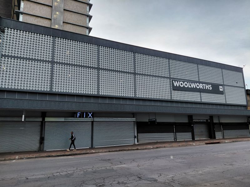 Street-level view of a commercial building facade featuring metal security shutters and decorative perforated metal cladding.