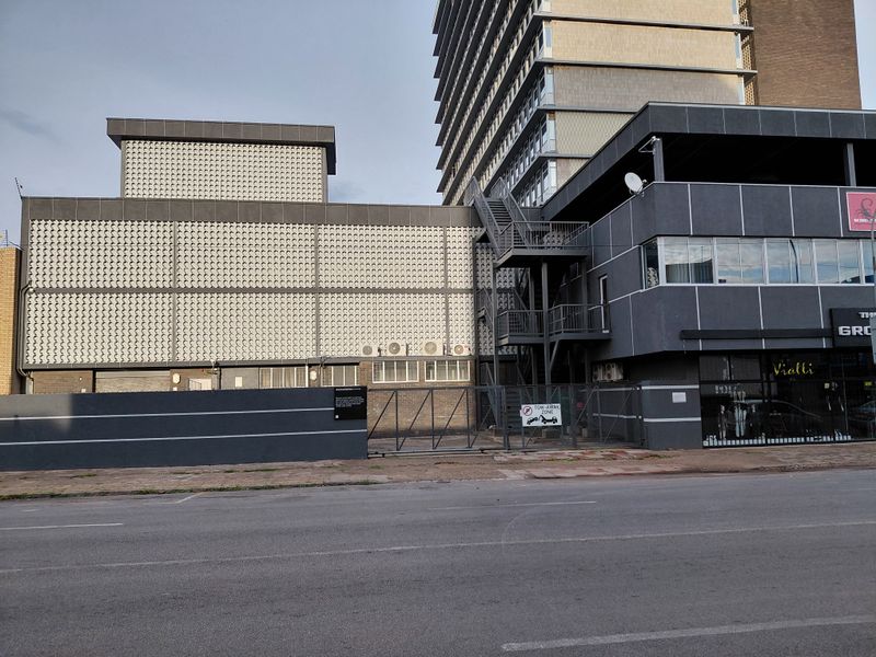 Exterior view of a commercial building featuring a modern facade, metal fire escape staircase, and secure gated entrance from the street.