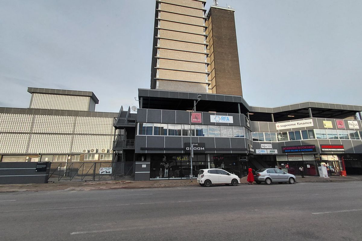 Street-level view of a multi-story commercial building featuring retail storefronts on the ground level and office space above.