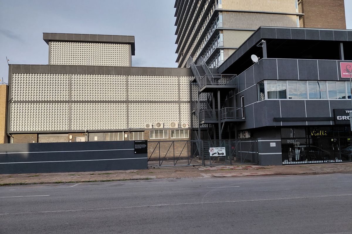 Exterior view of a commercial building featuring a modern facade, metal fire escape staircase, and secure gated entrance from the street.