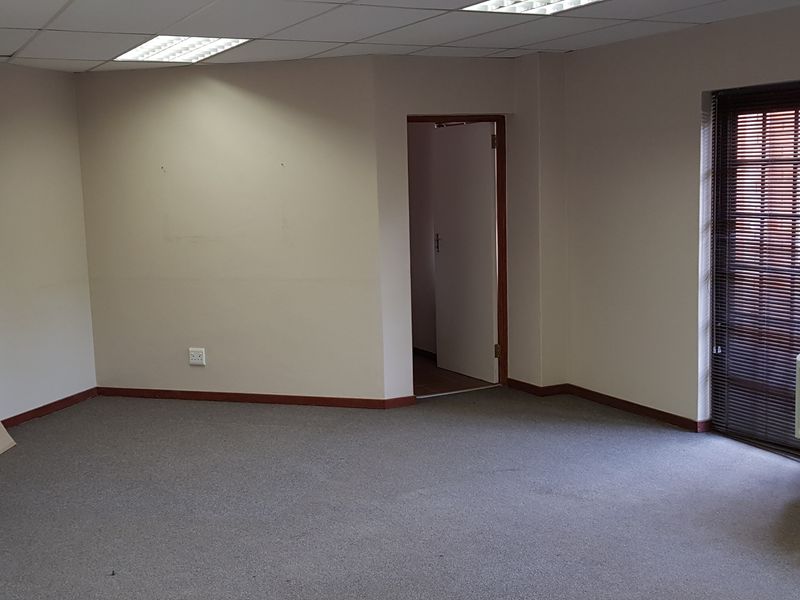 A vacant office space featuring carpeted flooring, a suspended ceiling with recessed lighting, and an integrated HVAC unit.