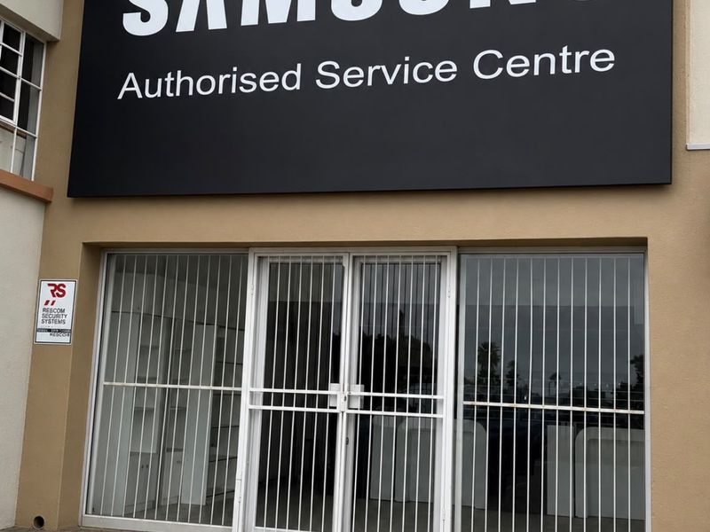 Front facade of an industrial service centre featuring prominent signage, secure gated entrance, and paved exterior area.