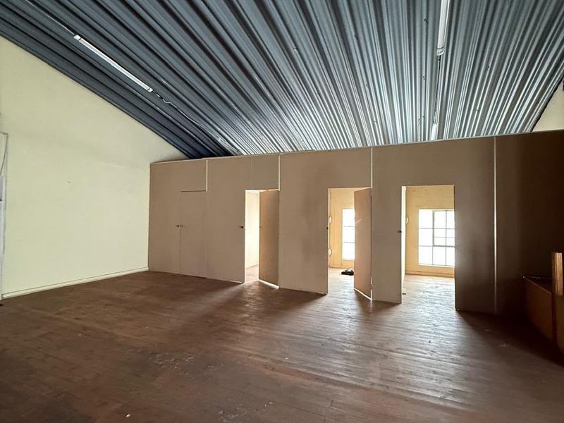 Spacious industrial utility area featuring a high corrugated metal ceiling, timber flooring, and multiple internal partition walls with access doors.