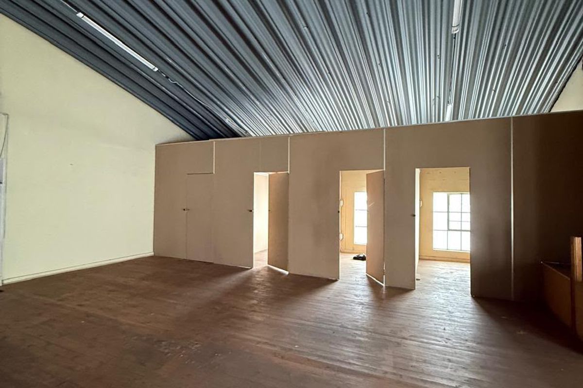 Spacious industrial utility area featuring a high corrugated metal ceiling, timber flooring, and multiple internal partition walls with access doors.