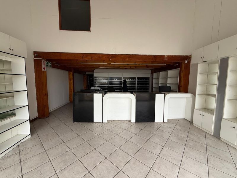 Spacious industrial office area featuring built-in reception counters, extensive shelving units, tiled flooring, and exposed timber ceiling beams.