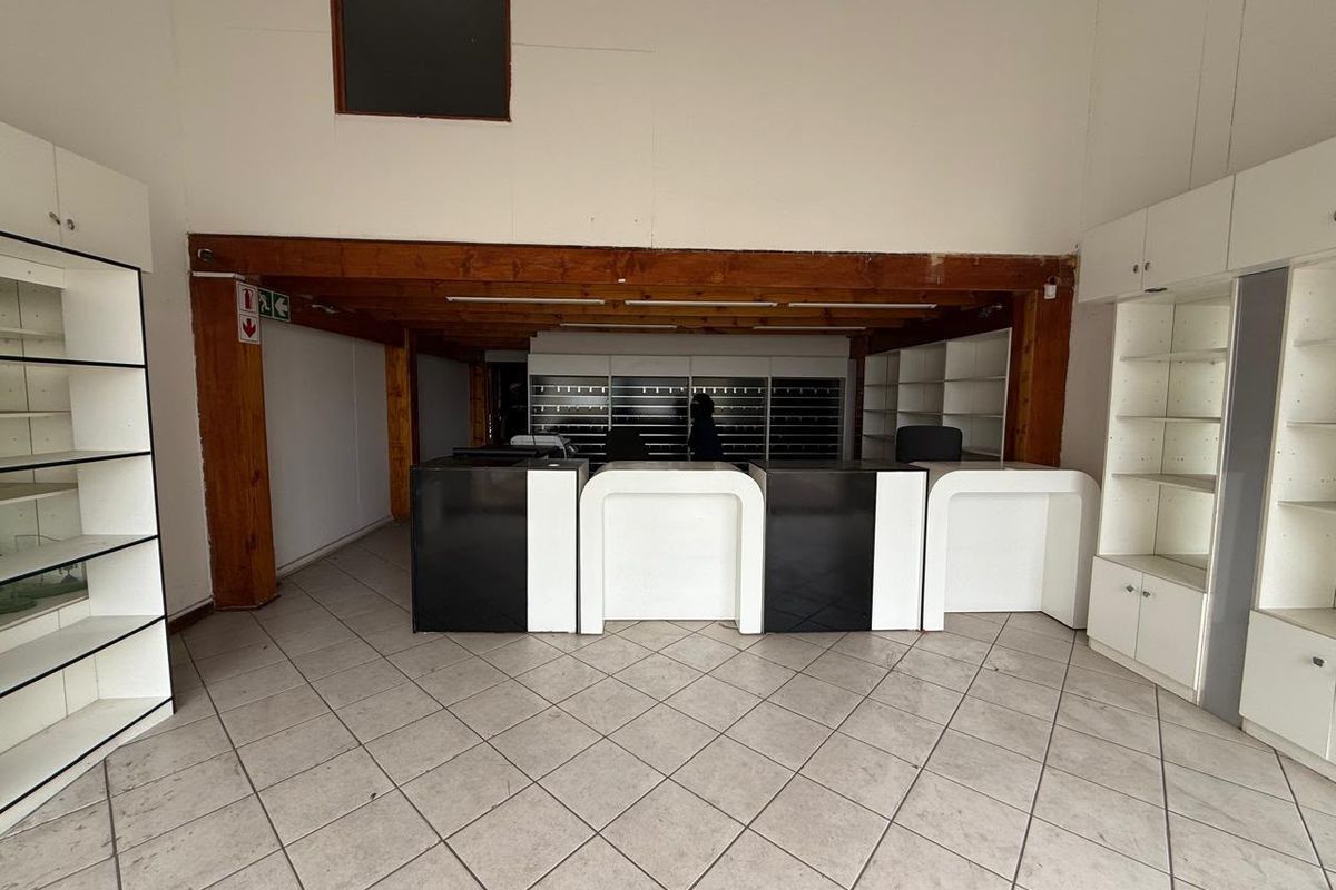 Spacious industrial office area featuring built-in reception counters, extensive shelving units, tiled flooring, and exposed timber ceiling beams.