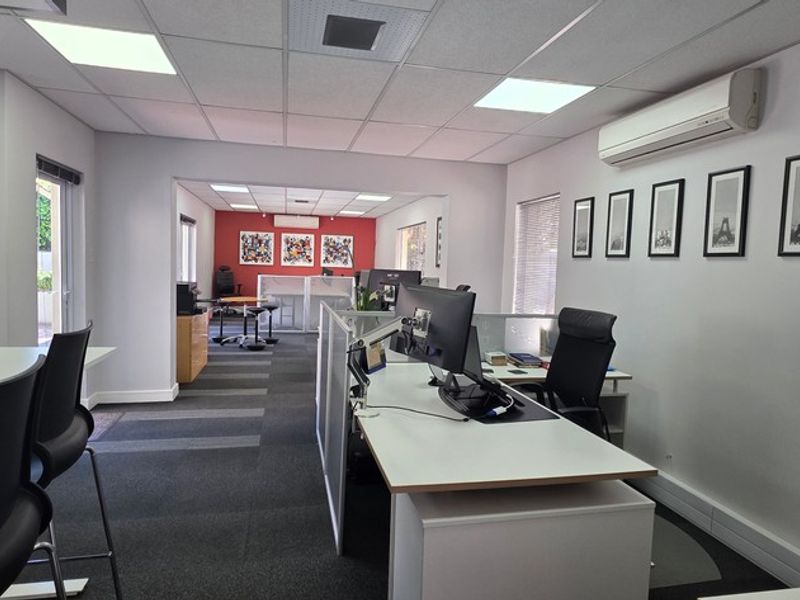 A well-maintained open-plan office space featuring suspended ceilings, recessed lighting, split-system air conditioning, and modern glass partitions.