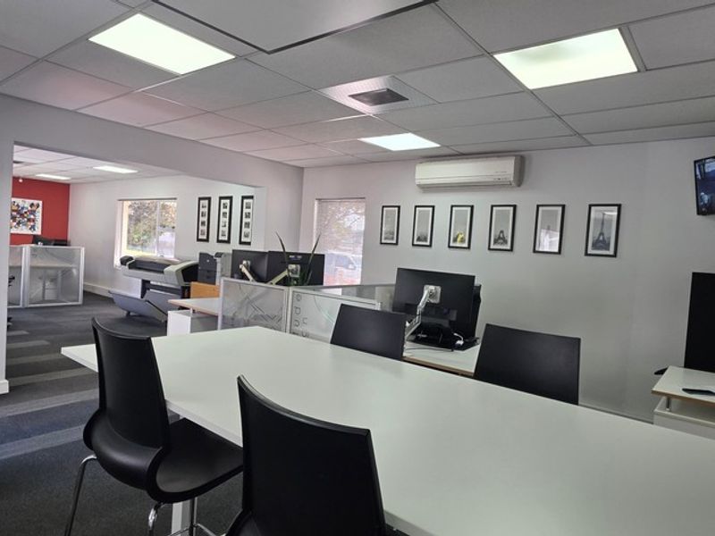 A functional office space featuring a suspended ceiling, recessed lighting, air conditioning, and carpeted flooring, providing a professional work environment.