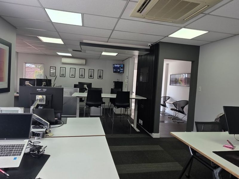 A modern, well-maintained open-plan office space featuring suspended ceilings, recessed lighting, ducted air conditioning, and professional carpeted flooring.