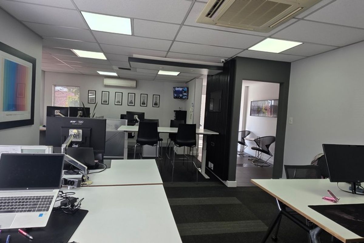A modern, well-maintained open-plan office space featuring suspended ceilings, recessed lighting, ducted air conditioning, and professional carpeted flooring.