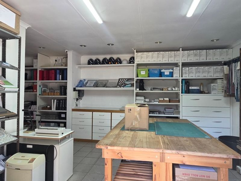 Functional office or workspace featuring extensive built-in shelving, cabinetry, and practical tiled flooring, suitable for storage or administrative tasks.