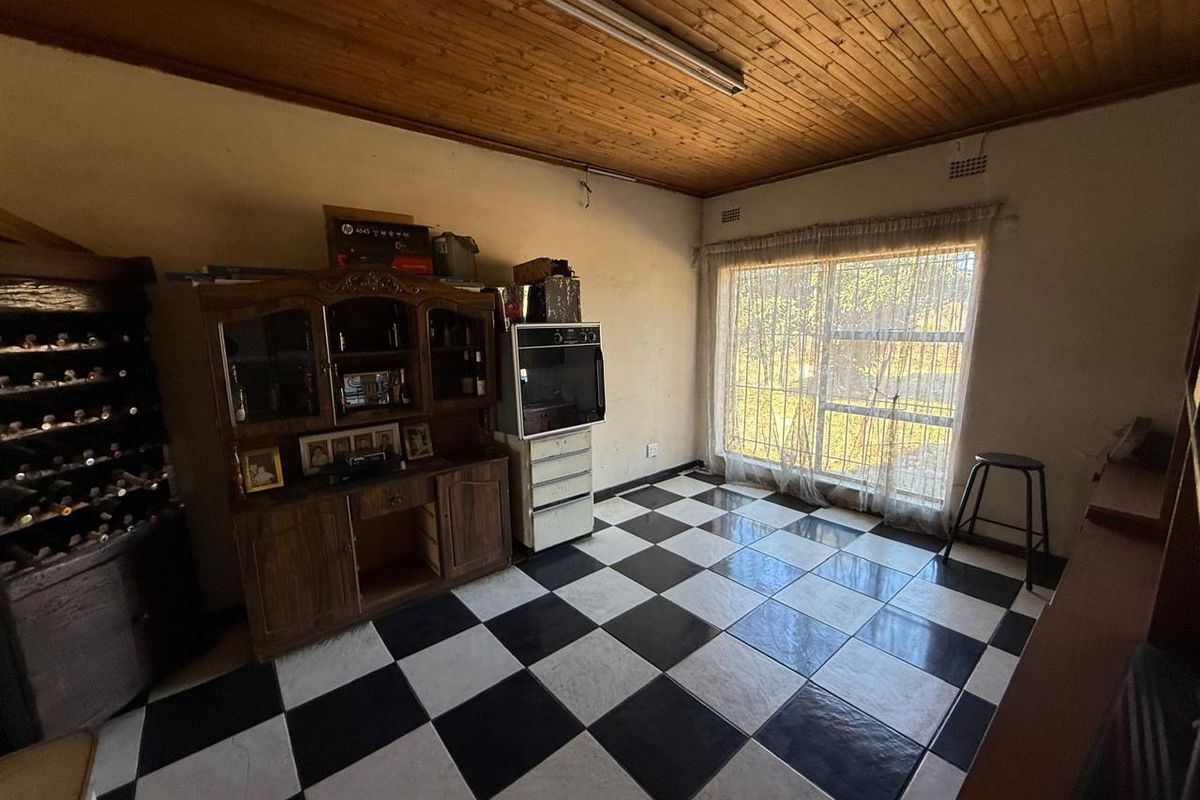A dated kitchen area featuring a timber ceiling, checkered floor tiles, and a built-in oven, offering potential for modernization and renovation.