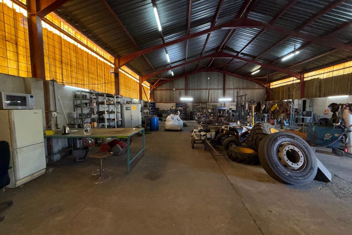 Spacious industrial utility area featuring a high-clearance steel portal frame, concrete flooring, and translucent wall panels providing natural light.