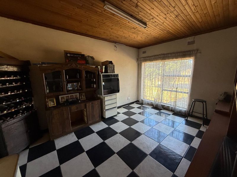 A dated kitchen area featuring a timber ceiling, checkered floor tiles, and a built-in oven, offering potential for modernization and renovation.