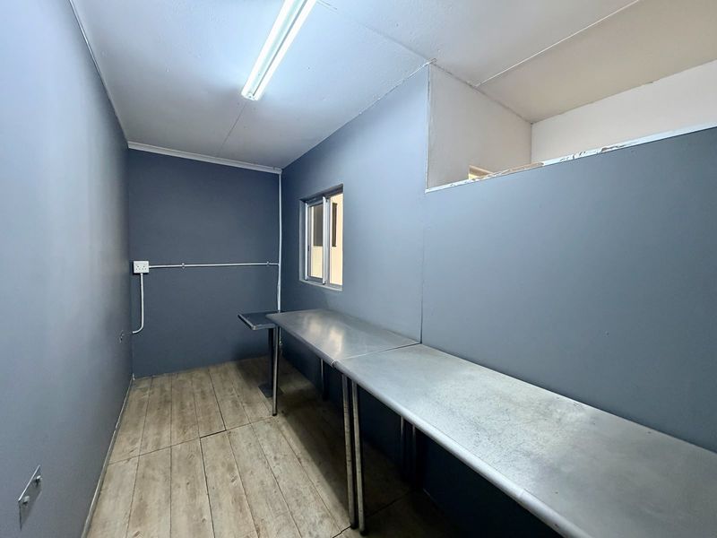 A functional utility or prep space featuring stainless steel work surfaces, wood-look flooring, and surface-mounted electrical infrastructure.