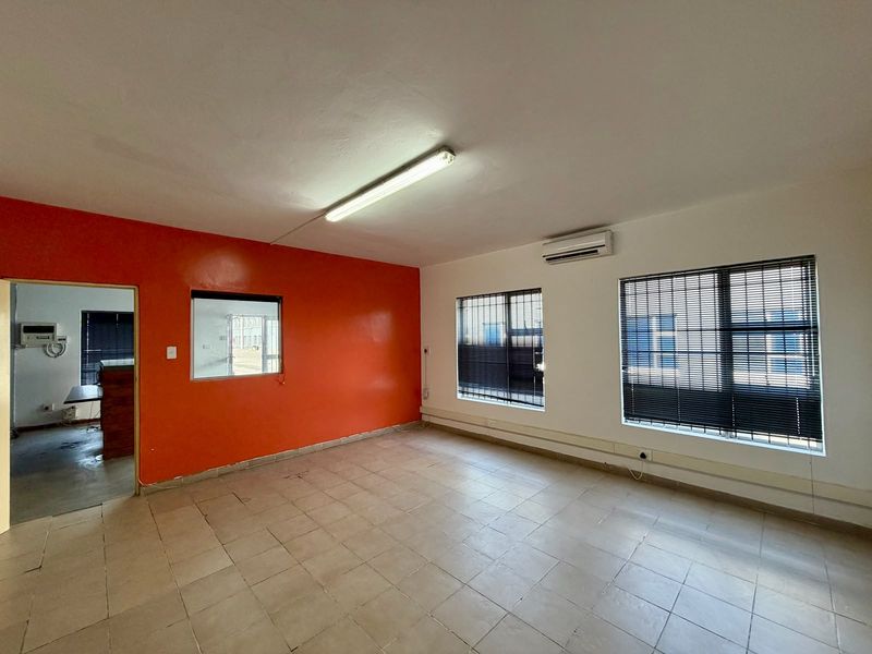 Empty commercial office space featuring tiled flooring, split-system air conditioning, and large windows with venetian blinds.