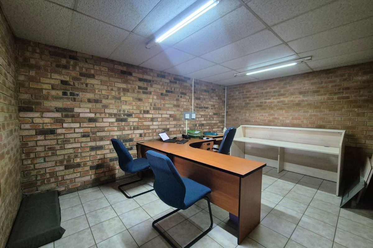 Functional office space featuring exposed brick walls, ceramic tile flooring, suspended ceiling, and a built-in reception counter.