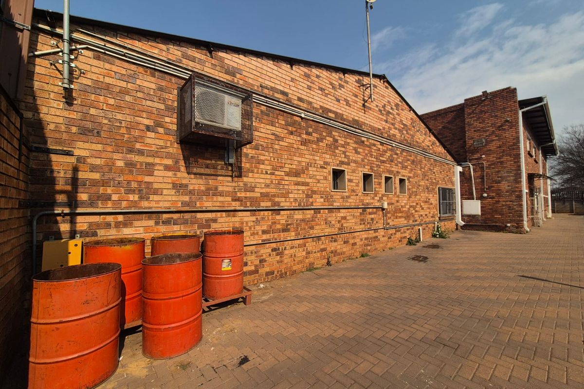 Rear exterior view of the office building featuring a face brick facade, paved courtyard area, and wall-mounted HVAC unit.