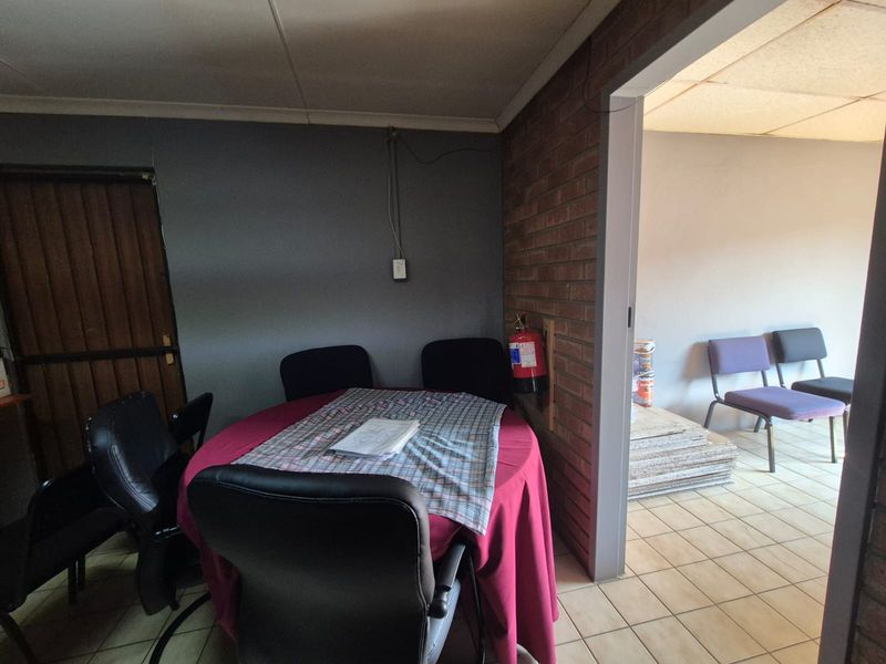 Office space featuring exposed brickwork, tiled flooring, and a drop ceiling, currently configured as a meeting area.