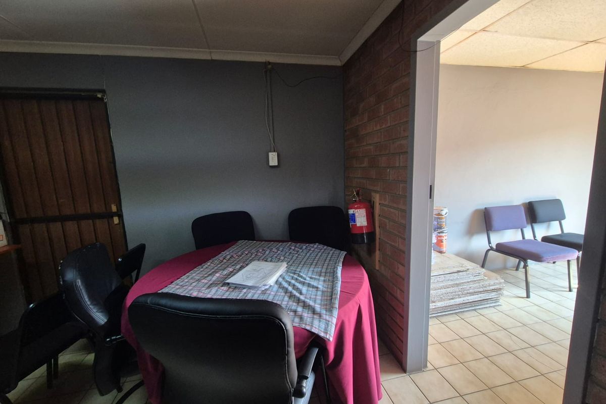 Office space featuring exposed brickwork, tiled flooring, and a drop ceiling, currently configured as a meeting area.