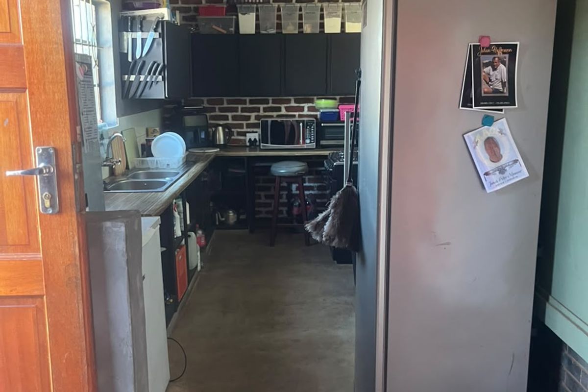 A compact industrial-style kitchen featuring exposed brick walls, dark cabinetry, and a stainless steel sink, offering a functional workspace with a rustic aesthetic.