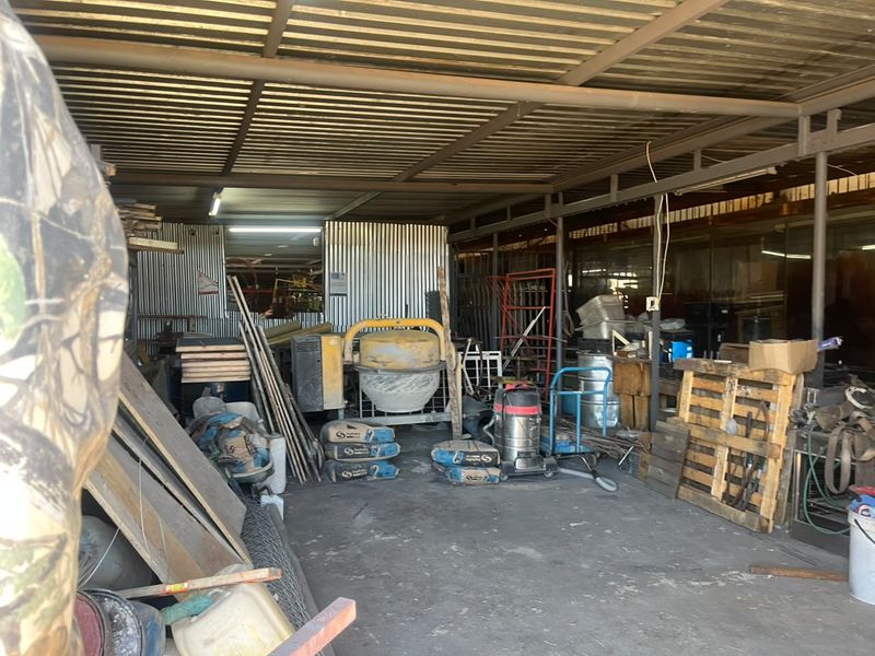 Industrial utility space featuring corrugated metal walls and roofing with concrete flooring, suitable for storage or workshop activities.