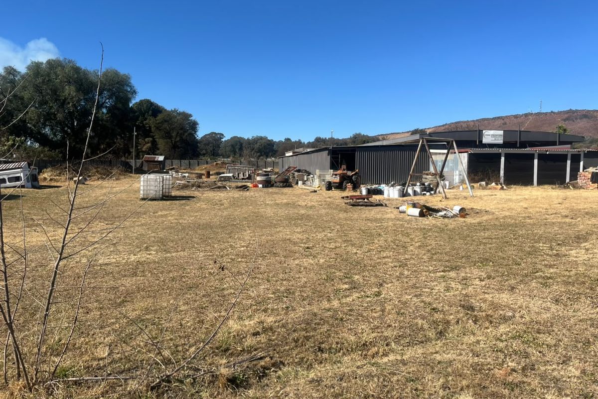 Expansive industrial yard area featuring a large corrugated metal shed structure and perimeter fencing, suitable for storage or operational use.