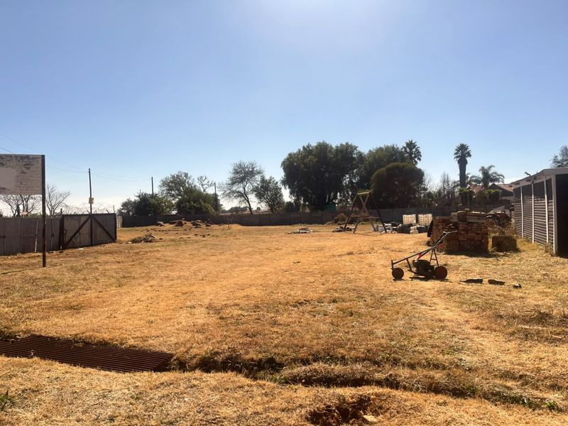 A large, open industrial yard area featuring perimeter fencing with razor wire and a metal gate, providing significant space for development or storage.