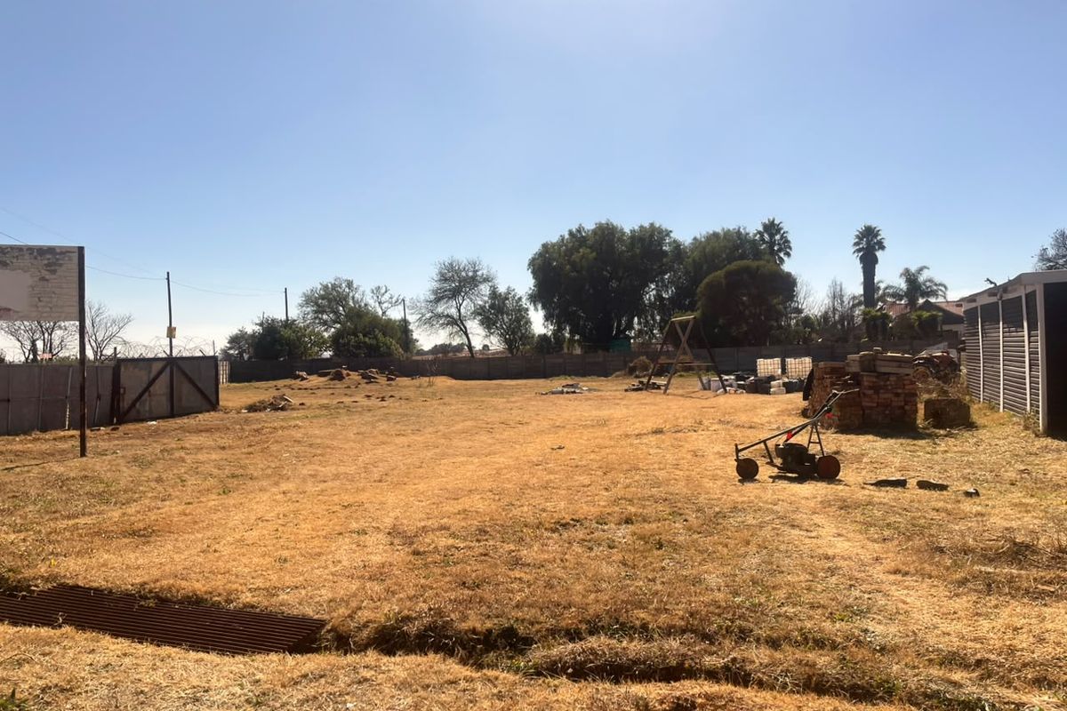 A large, open industrial yard area featuring perimeter fencing with razor wire and a metal gate, providing significant space for development or storage.