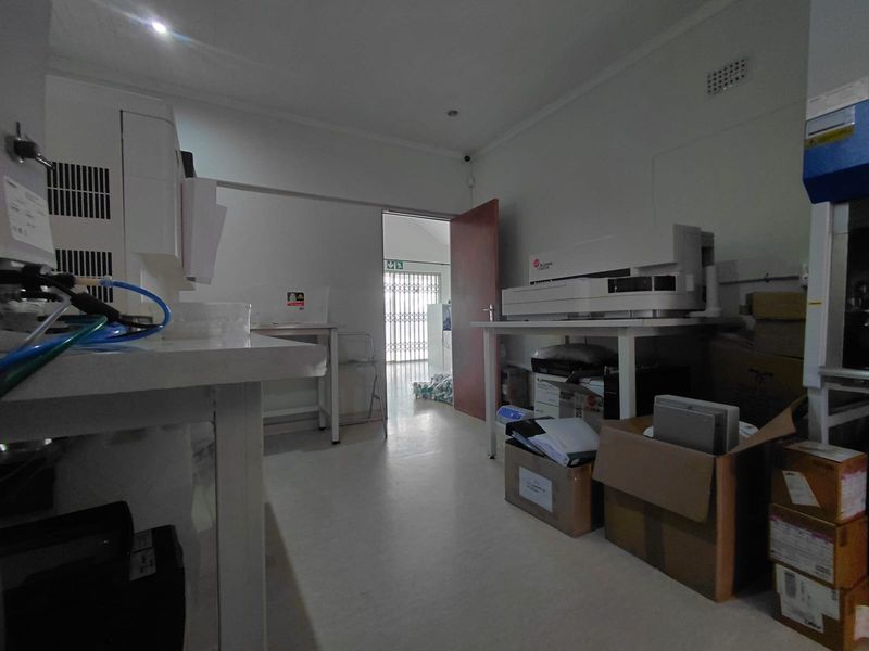 A functional utility or laboratory space featuring fixed work surfaces, recessed lighting, and a secure rear access point.