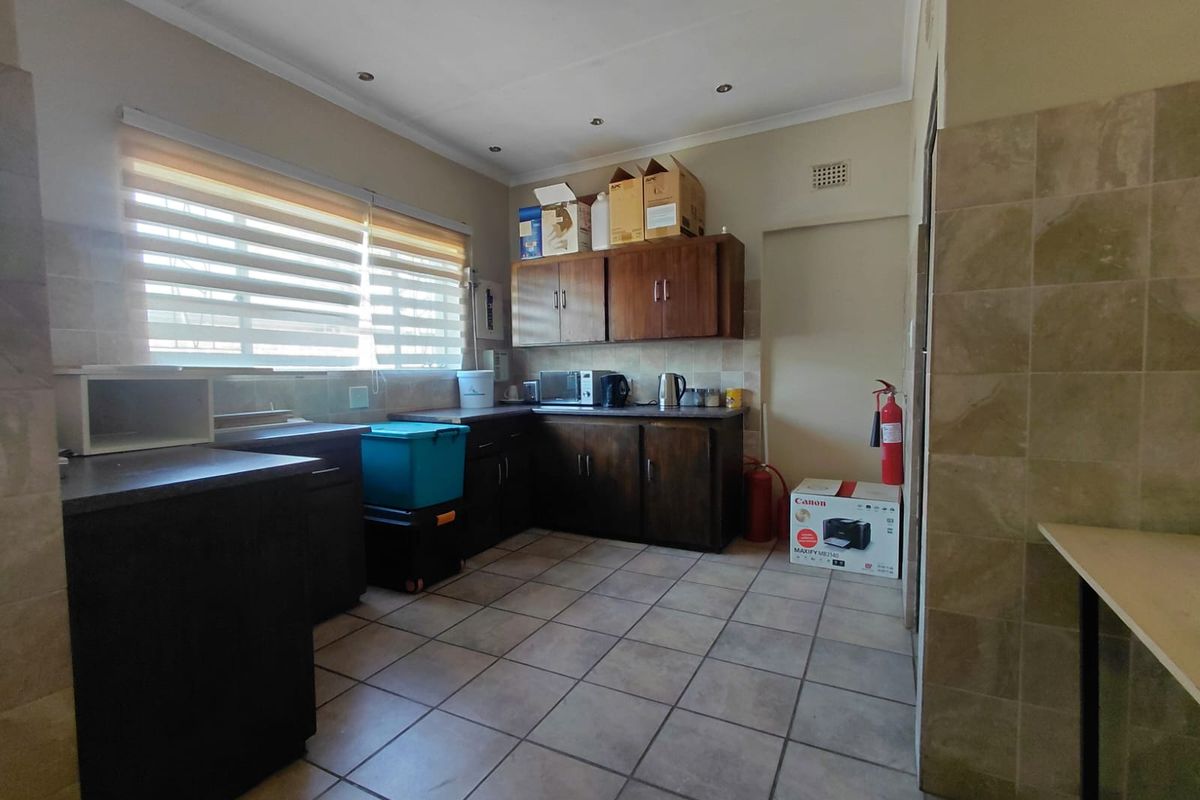 A functional kitchen area featuring dark wood cabinetry, tiled flooring, and tiled splashbacks, equipped with recessed lighting and window blinds.