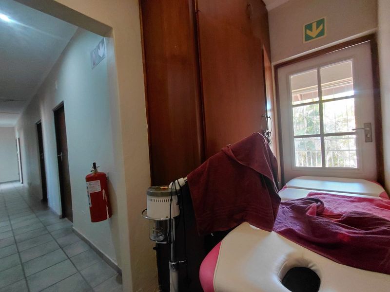 A functional utility or treatment room featuring built-in cabinetry, a fire extinguisher, and an emergency exit door leading to an outdoor area.