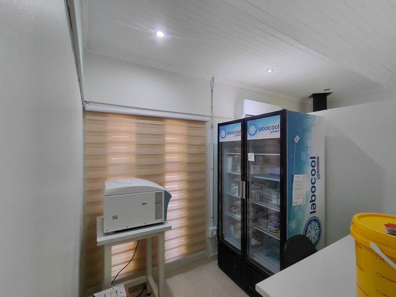 A functional utility or laboratory space featuring recessed lighting, timber ceiling finishes, and a wall-mounted air conditioning unit.