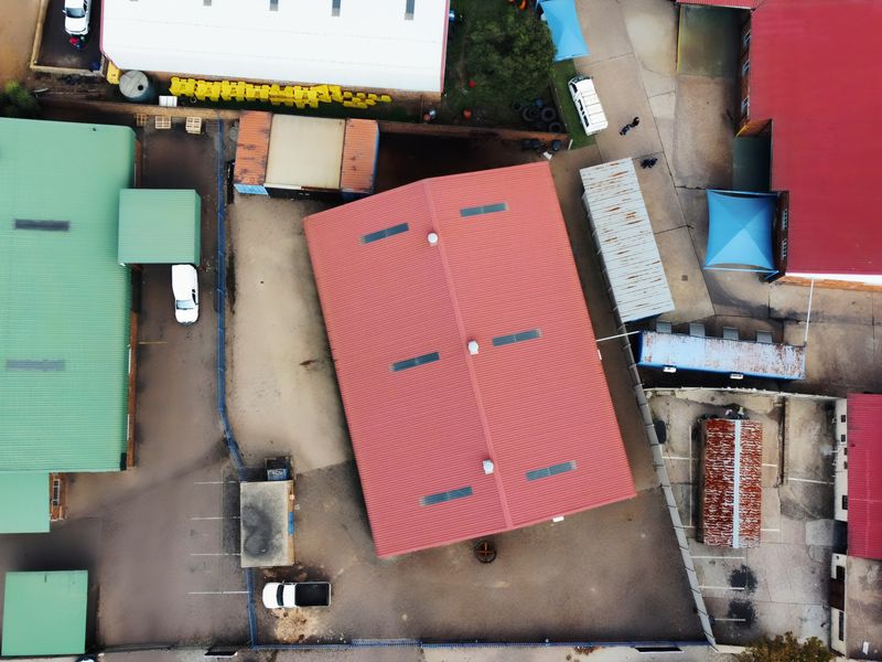 Aerial view of an industrial property complex featuring multiple warehouse buildings with metal roofing, skylights, and paved yard space.