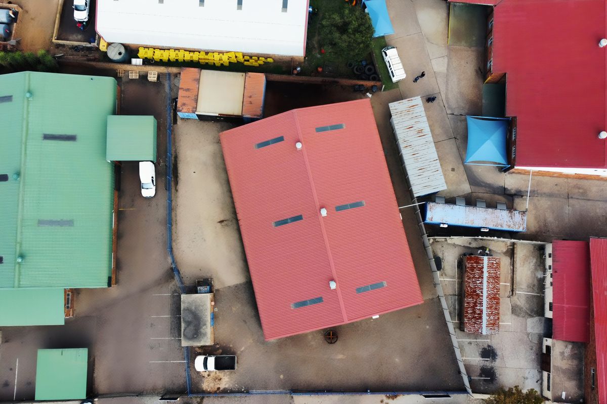 Aerial view of an industrial property complex featuring multiple warehouse buildings with metal roofing, skylights, and paved yard space.