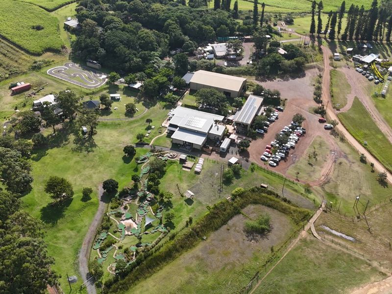 Aerial view of a commercial office property featuring extensive grounds, a miniature golf course, solar-equipped buildings, and a dedicated paved parking area.