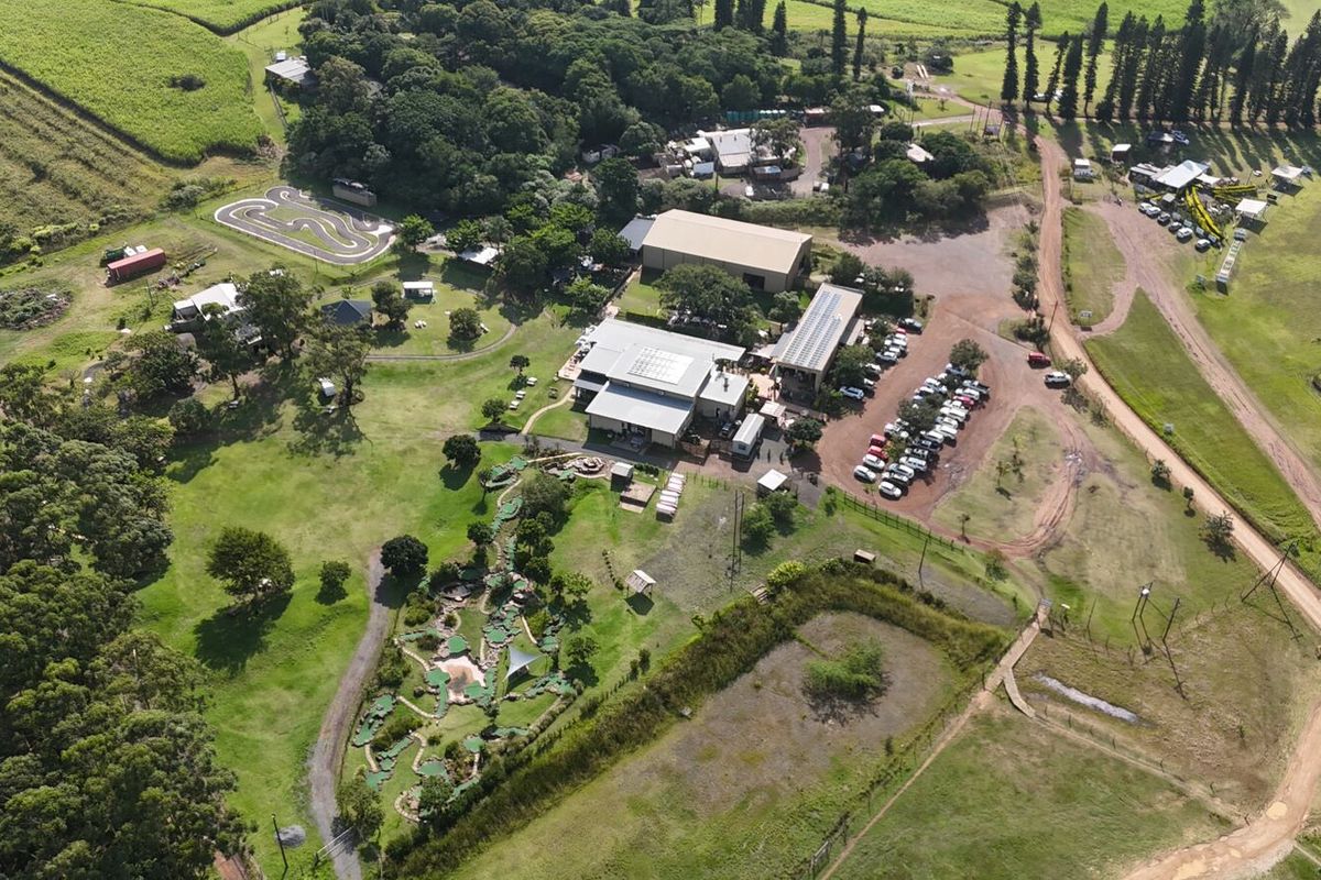 Aerial view of a commercial office property featuring extensive grounds, a miniature golf course, solar-equipped buildings, and a dedicated paved parking area.