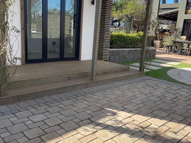 A well-maintained outdoor patio area featuring timber decking, a pergola, and paved flooring, providing a clean and inviting entrance to the office space.