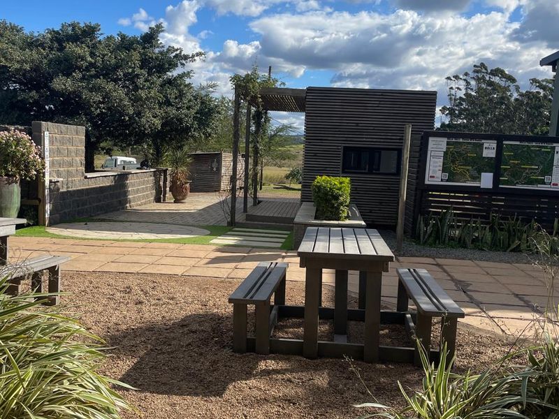 Outdoor patio area featuring paved flooring, a timber pergola, and modern timber-clad structure, suitable for office break-out or recreational use.