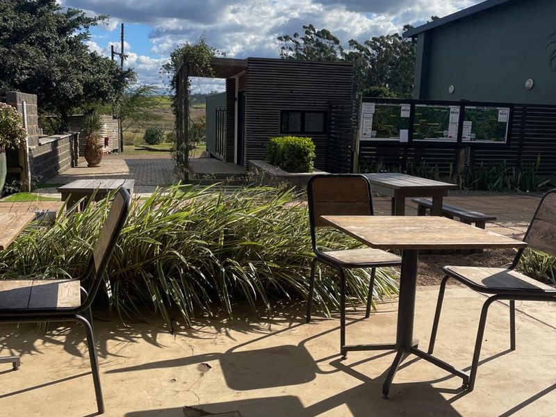 Outdoor patio area featuring concrete flooring and a timber-slatted structure, providing an open-air space for office staff or visitors.