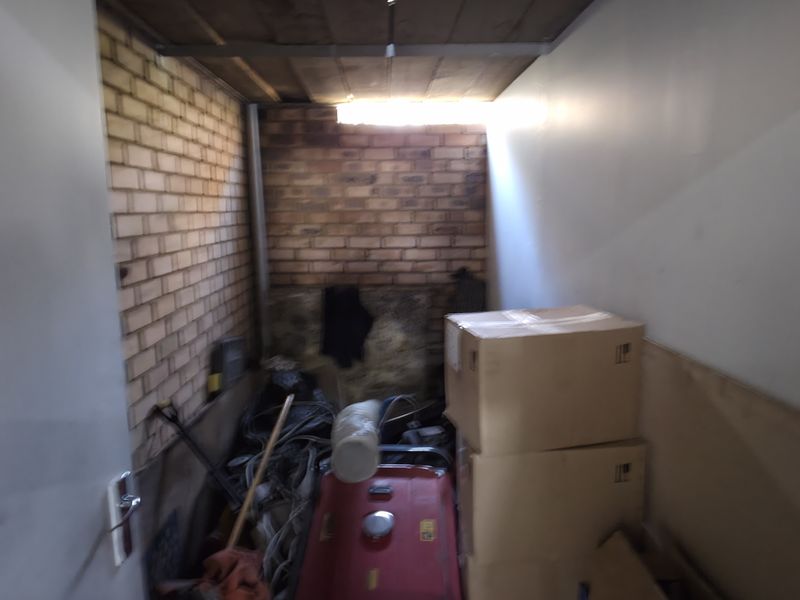 A compact utility or storage space featuring exposed brick walls and a timber ceiling, suitable for various industrial or workshop storage needs.