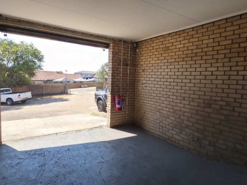A spacious, empty industrial-style garage featuring exposed brick walls and durable concrete flooring, suitable for vehicle storage or workshop use.