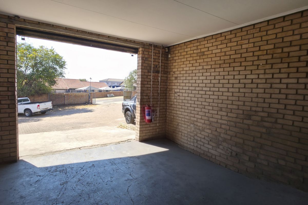 A spacious, empty industrial-style garage featuring exposed brick walls and durable concrete flooring, suitable for vehicle storage or workshop use.