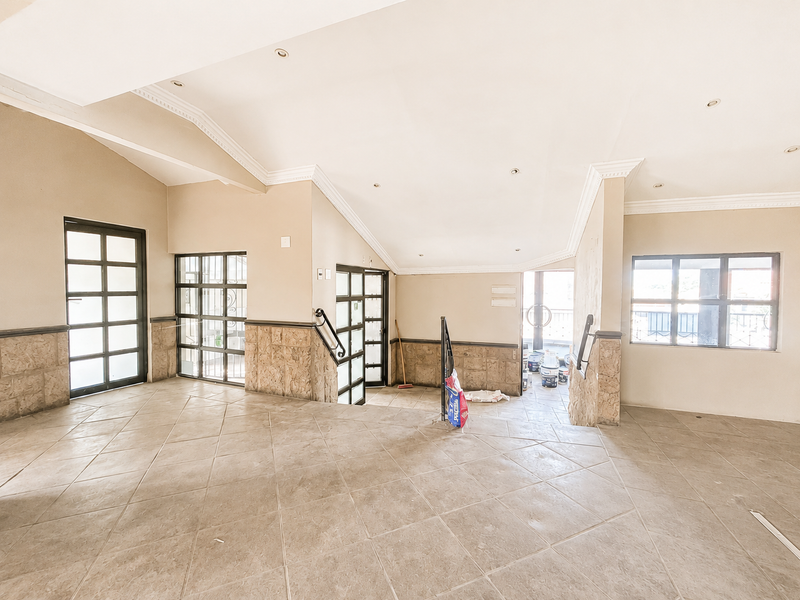 Spacious office interior featuring tiled flooring, stone wall accents, recessed lighting, and multiple glass-paneled doors and windows providing natural light.