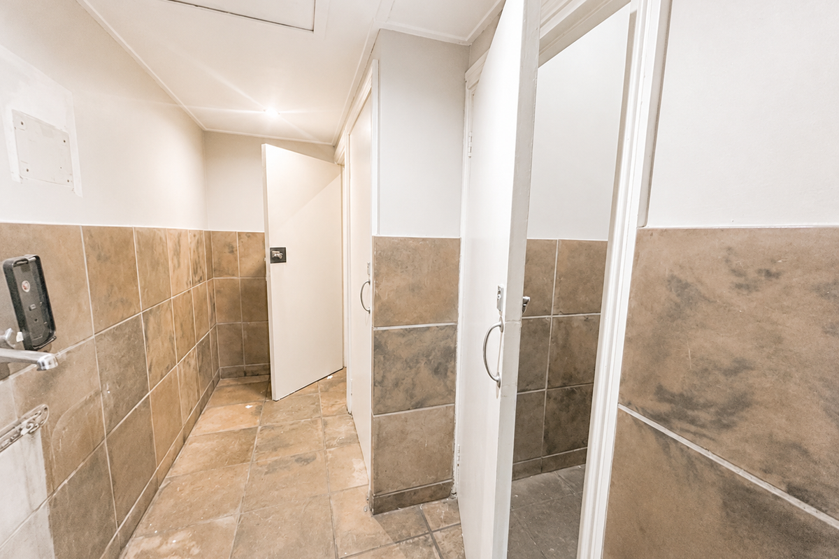 A functional bathroom area featuring tiled walls and flooring with multiple access doors, requiring cosmetic updates to improve the overall condition.