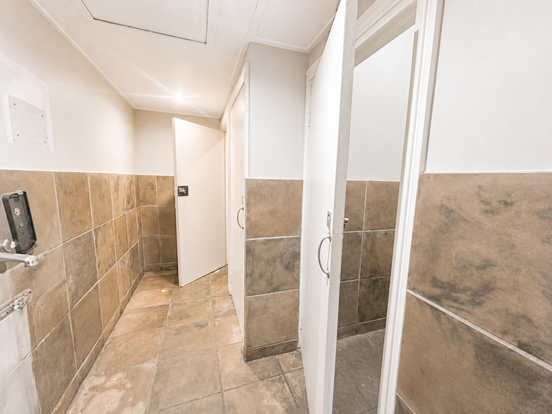A functional bathroom area featuring tiled walls and flooring with multiple access doors, requiring cosmetic updates to improve the overall condition.
