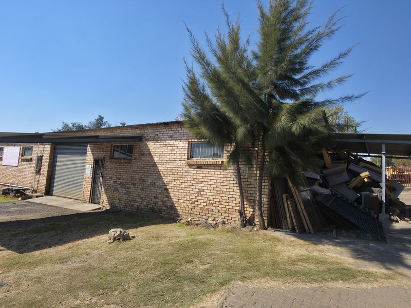 Industrial property featuring a face brick facade, roller shutter door access, and an attached steel carport structure.