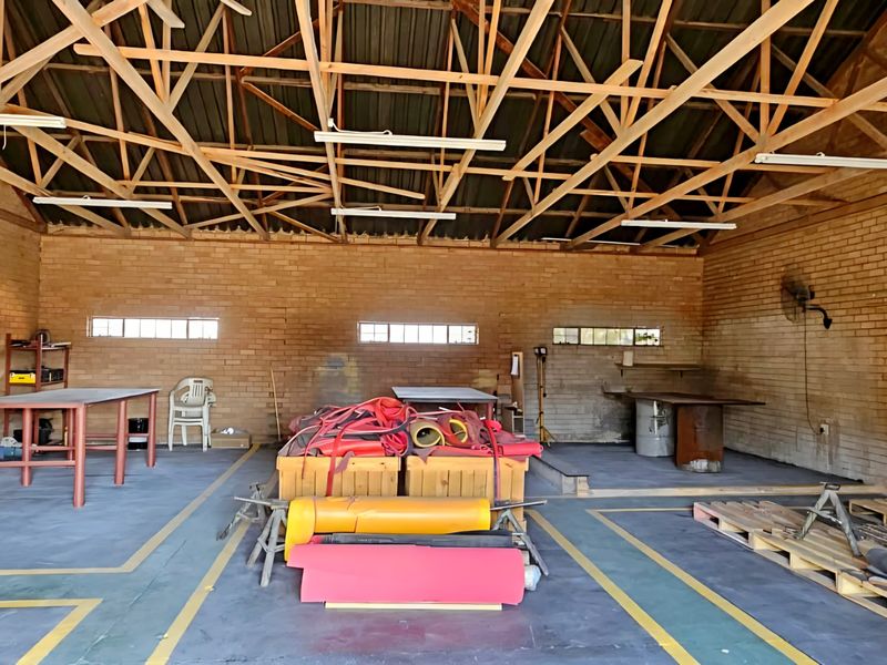 Spacious industrial utility area featuring exposed timber roof trusses, face brick walls, and durable concrete flooring with high-level windows for natural light.