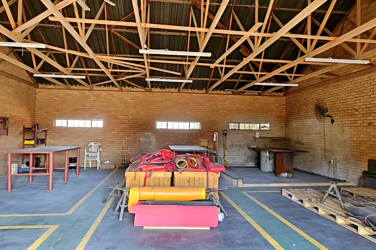 Spacious industrial utility area featuring exposed timber roof trusses, face brick walls, and durable concrete flooring with high-level windows for natural light.