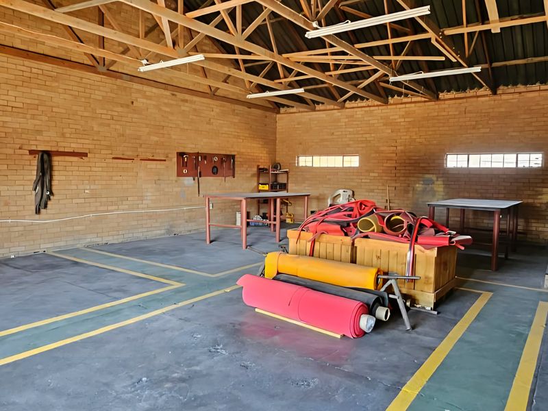Spacious industrial utility area featuring exposed timber roof trusses, brick walls, and durable concrete flooring with painted safety markings.